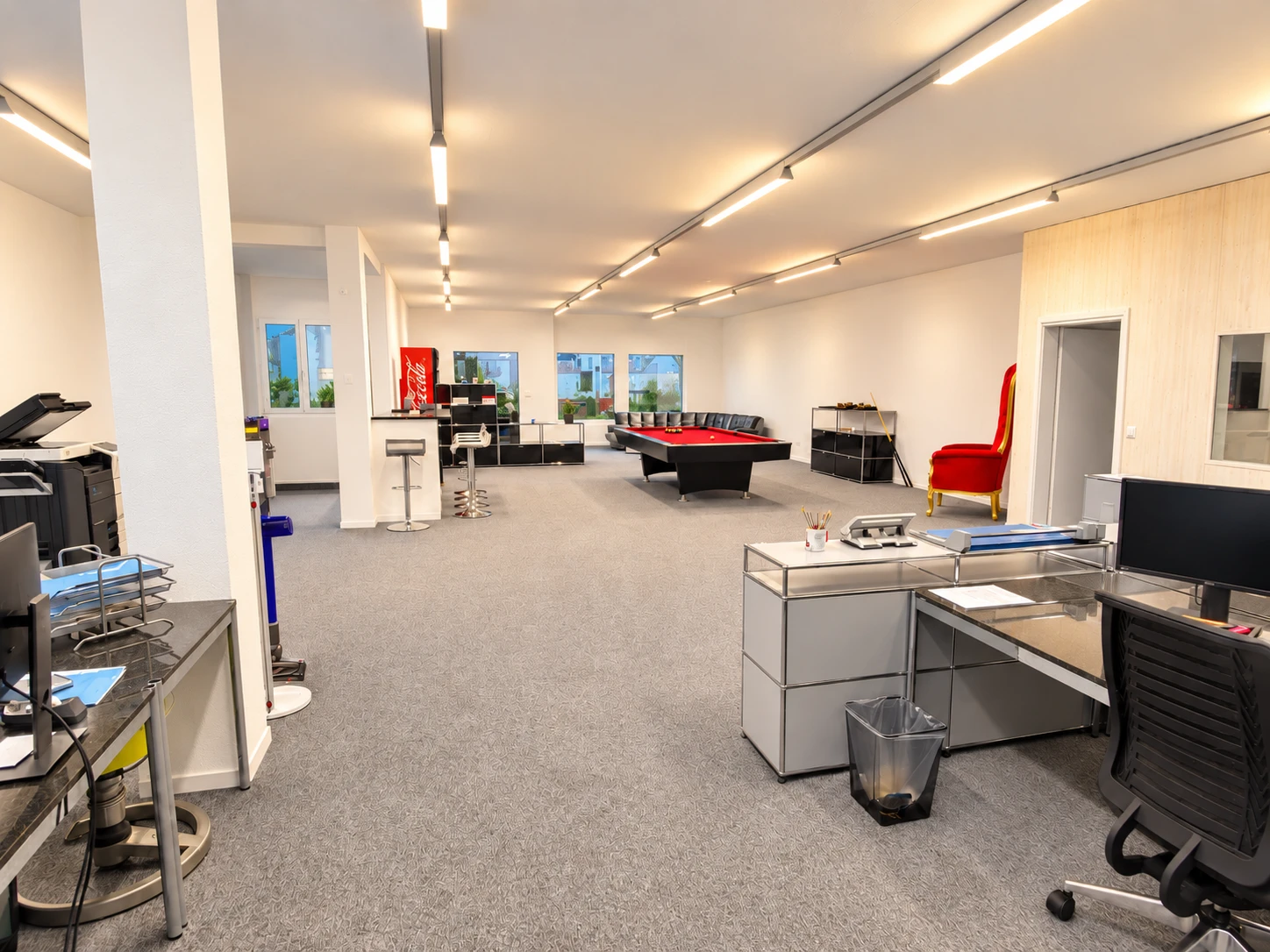 Offene Büro- und Ladenfläche mit Fensterfront, Sitzgruppe und Industrieteppich